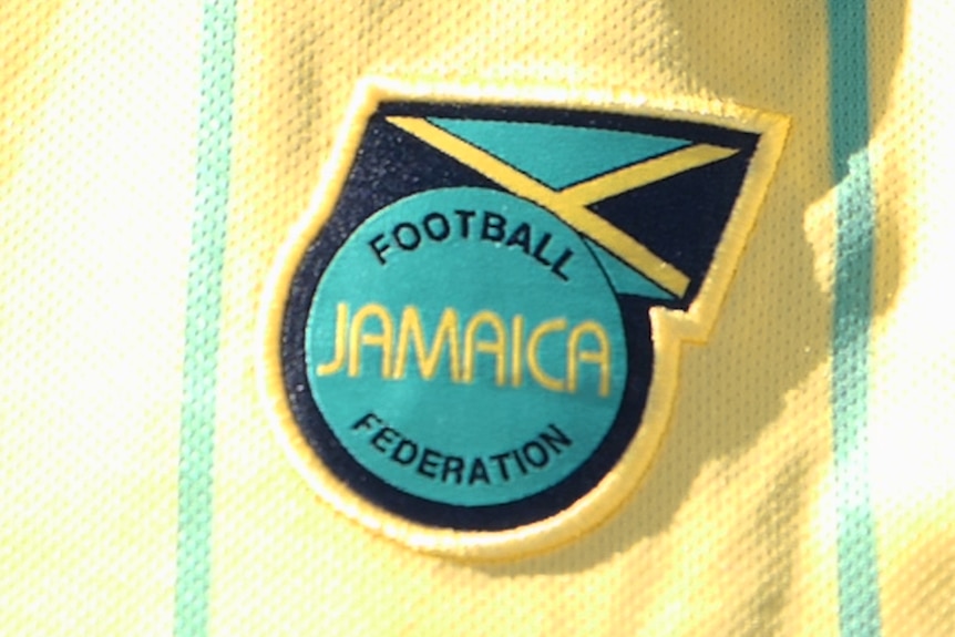 A closeup of the Football Federation Jamaica logo on a yellow playing shirt.