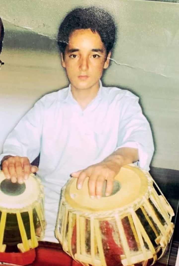 A young man sits with his hands on tabla drums