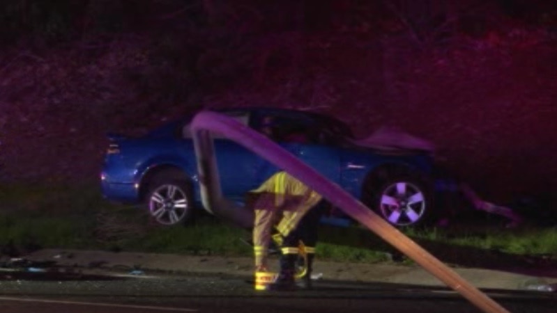 A destroyed and bent street pole and a damaged blue car.