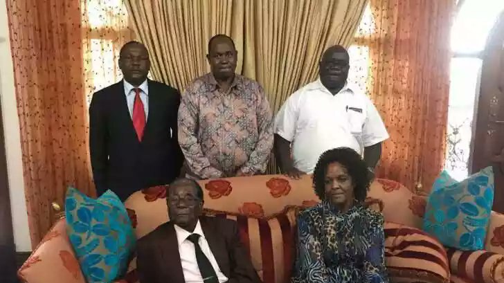 Former Zimbabwe President Robert Mugabe sits on a couch with his wife Grace and extended family around him