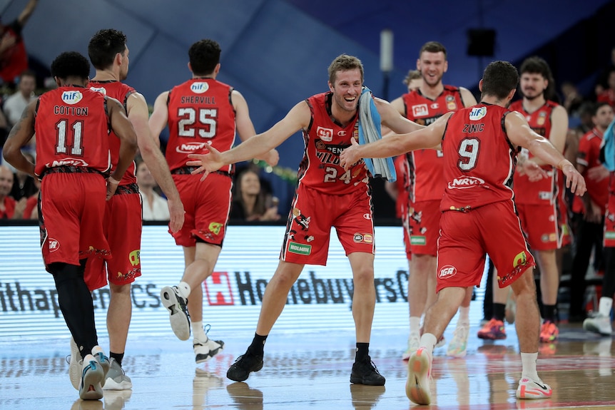 A basketball team wearing a red jersey celebrates on the court