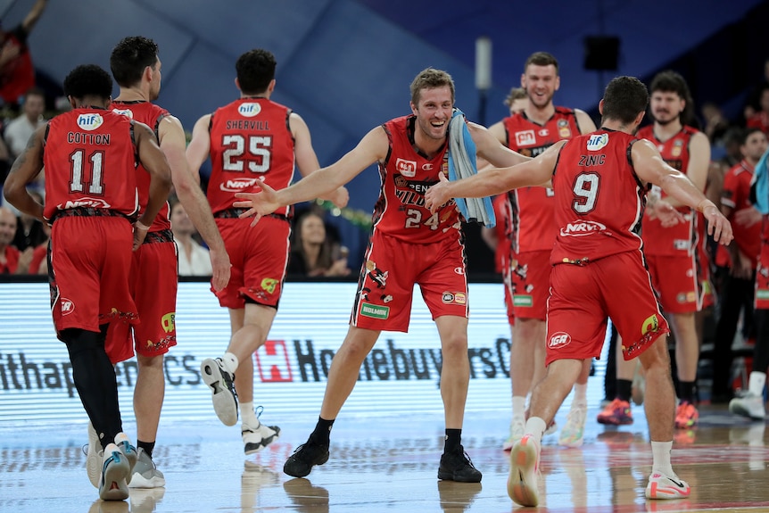 Une équipe de basket portant un maillot rouge célèbre sur le terrain