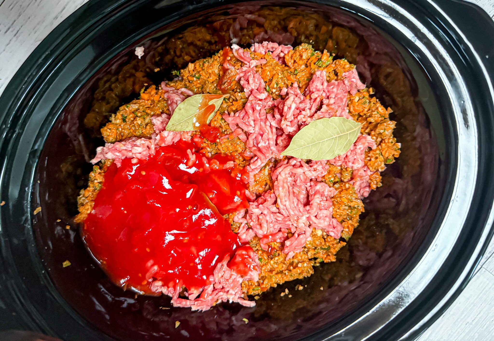 Blitzed vegetables, minced beef and pork, tinned tomatoes and bay leaves are layered in a slow cooker to make bolognese. It's