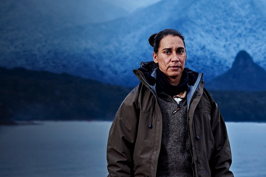 Head and shoulders image of a woman in outdoors cold-weather gear in front of an icy mountain backdrop.