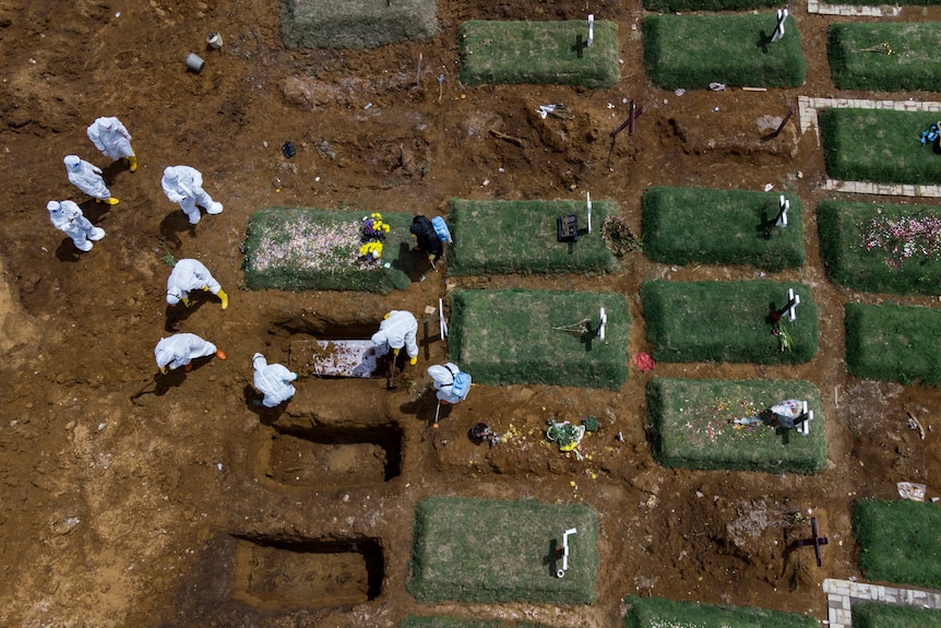 In an aerial view, workers bury a coffin containing the body of a COVID-19 victim
