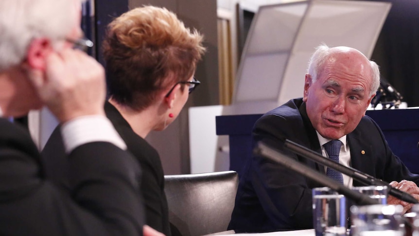 John Howard speaks to a woman on the panel at a National Press Club address, September 7, 2016.