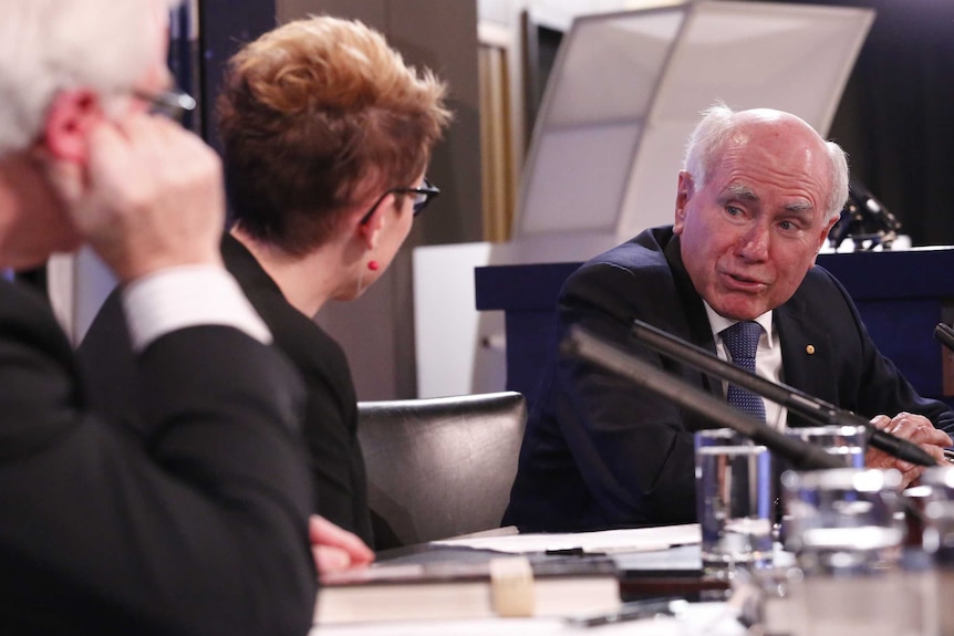 John Howard speaks to a woman on the panel at a National Press Club address, September 7, 2016.