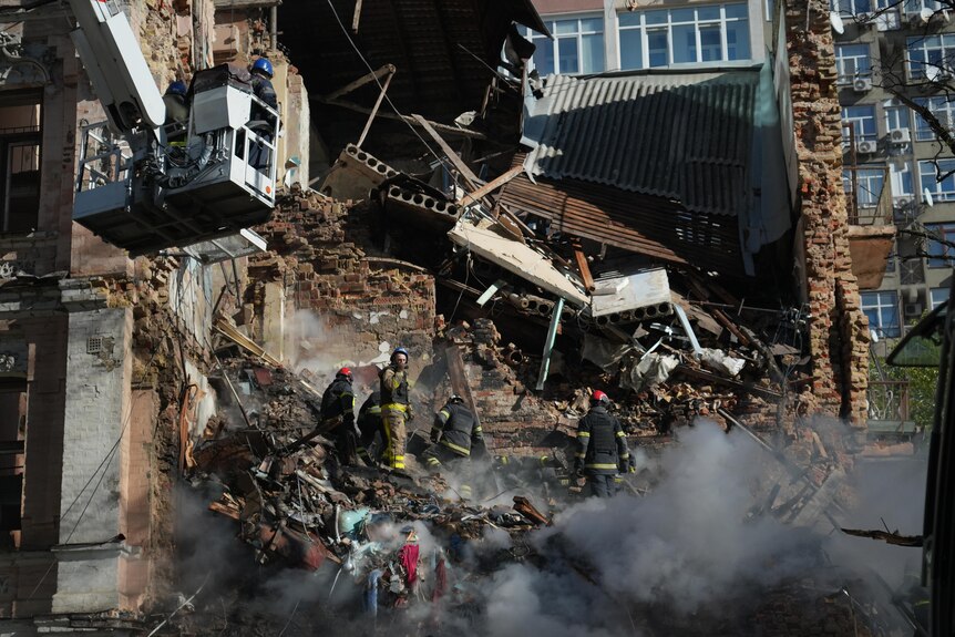 Emergency service workers sift through the rubble of an apartment building in Kyiv.