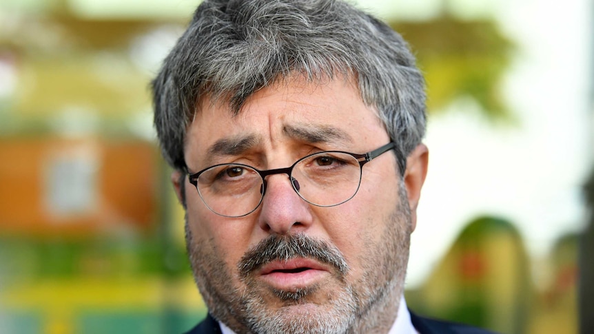 A close up shot of Brisbane barrister Sam Di Carlo wearing a suit and glasses.