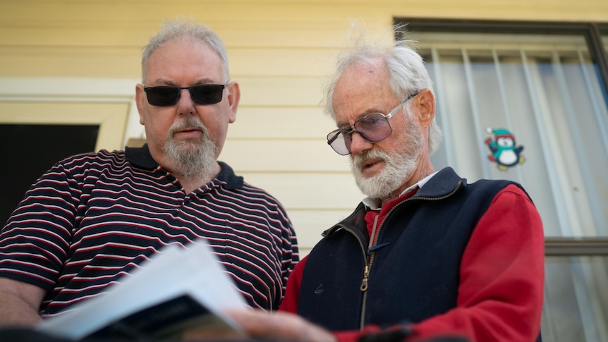Two men looking at solar power bill standing on front porch 