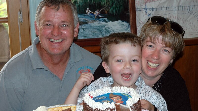 A boy with a birthday cake and his parents