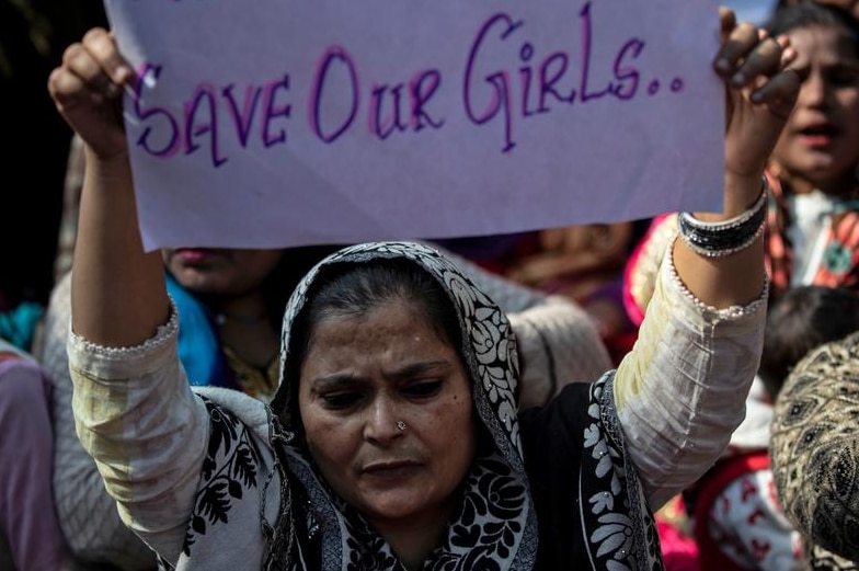 A protester holding up a sing saying safe our girls.