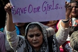 A protester holding up a sing saying safe our girls.