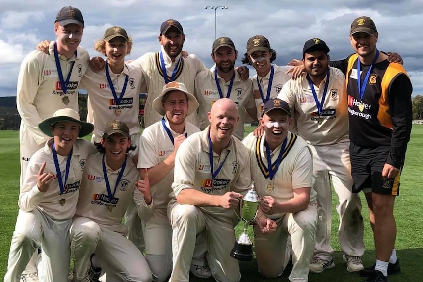 A group of Hobart club cricketers celebrate with a trophy.