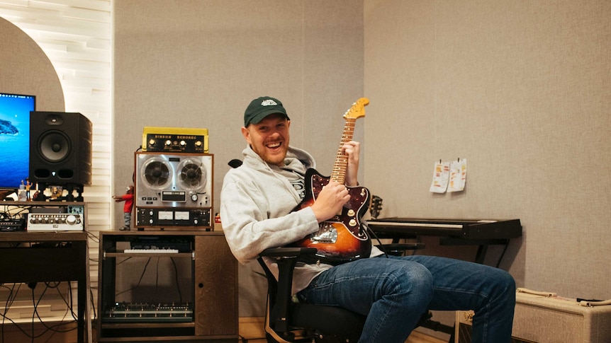 Kenny Beats in the studio, holding a guitar