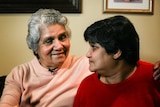 An elderly Indian woman smiles at her middle-aged daughter.