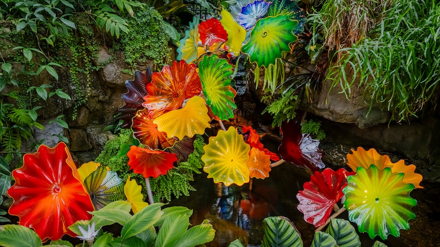 green, red and yellow glass art that looks like flowers, plants  and leaves