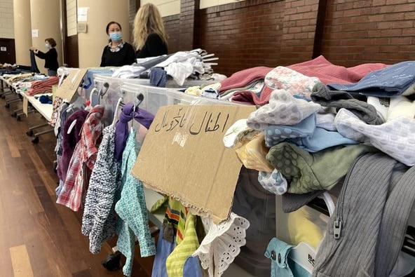 A table filled with clothes with a label written in Arabic letters to warn refugees.