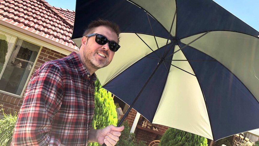 Damien MacRae holds an umbrella.
