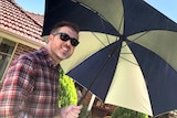 Damien MacRae holds an umbrella.