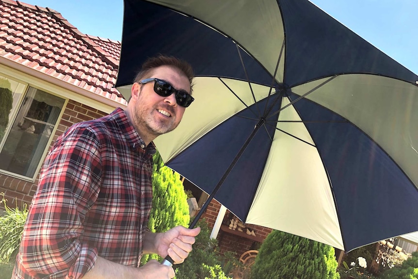 Damien MacRae holds an umbrella.