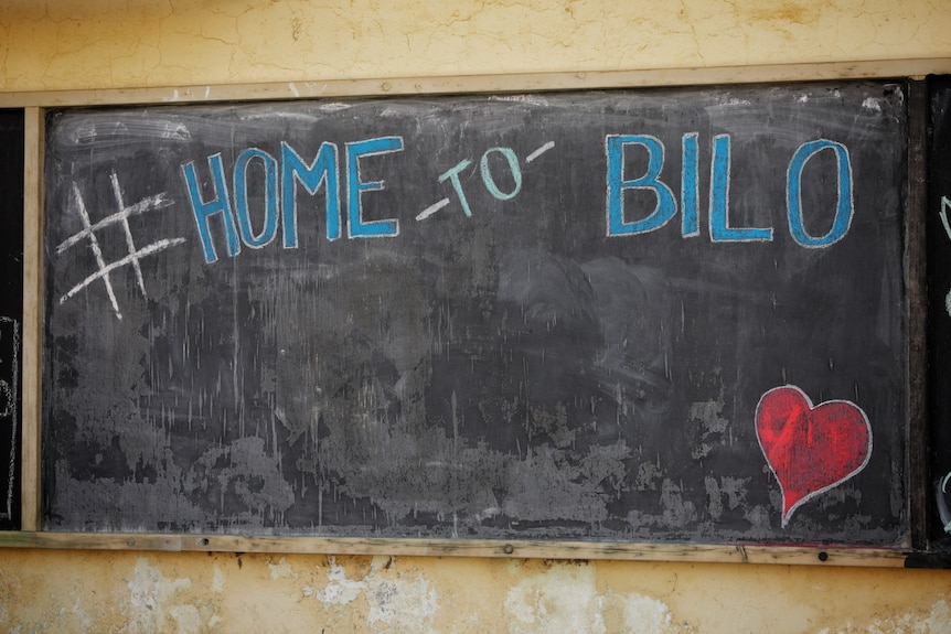 A message on a blackboard reads "home to Bilo".
