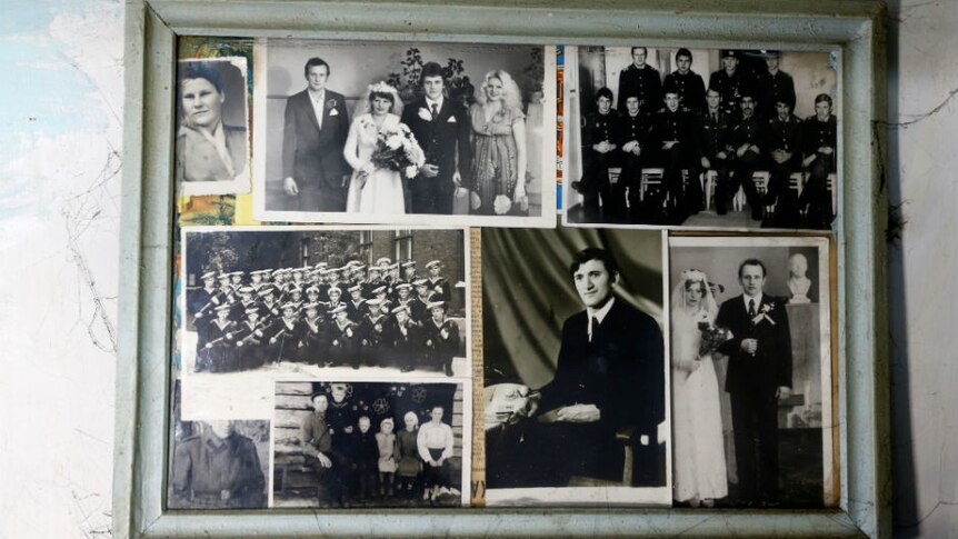 Black-and-white photographs of Ivan Shamyanok's relatives on display in a dusty frame in his house.