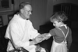A young girl receives a vaccination from a man in a white coat in an undated black and white photograph.