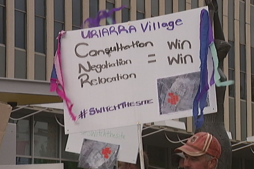 Uriarra residents angry about a proposed solar farm hold up a protest sign outside the ACT Legislative Assembly.