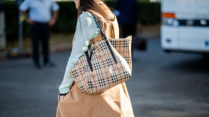 A woman carrying a Burberry label handbag