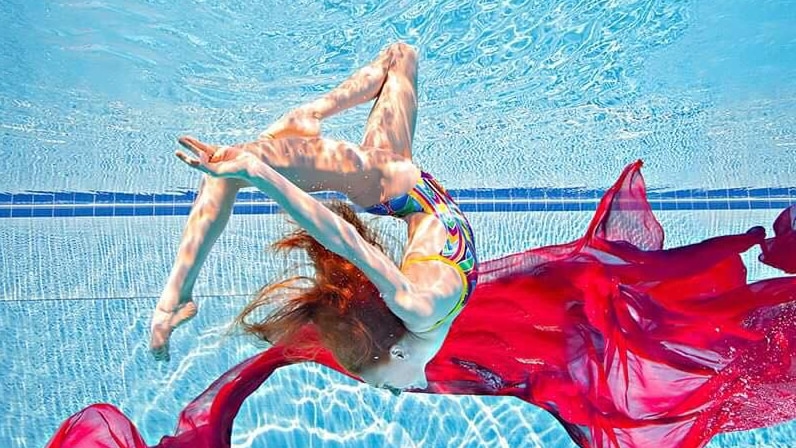 A female synchronised swimmer performs under water.