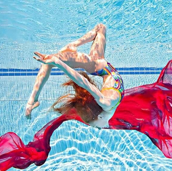 A female synchronised swimmer performs under water.