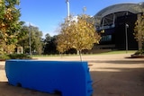 A blue concrete security barrier blocks part of a pathway at Adelaide Oval