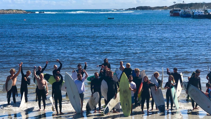 A group of surfers prepare to paddle out to protest against fish farm developments off King Island.