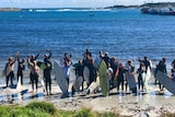 A group of surfers prepare to paddle out to protest against fish farm developments off King Island.