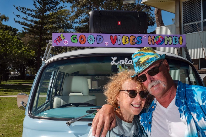 A woan and man stand in front of a van with a mounted speaker on the roof.