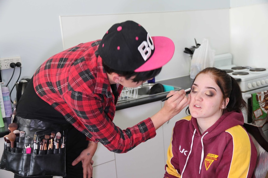 A makeup artist does eyeshadow on a client