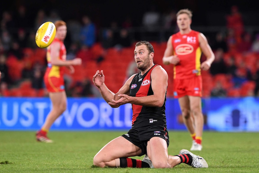 Tom Bellchambers slides on his knees to take a mark for the Bombers against the Suns.