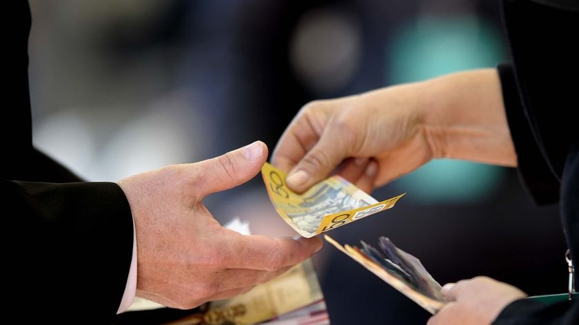 A close-up of a person handing a $50 note to another.