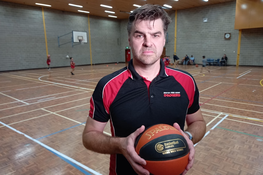 Grant looks serious, holding a basketball on a court.