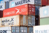 Shipping containers stacked up with logos for Maersk and Hamburg Sud on them