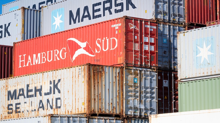 Shipping containers stacked up with logos for Maersk and Hamburg Sud on them