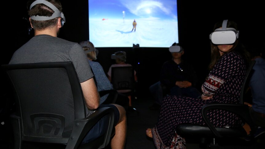 Two people sit in the dark with virtual reality headsets