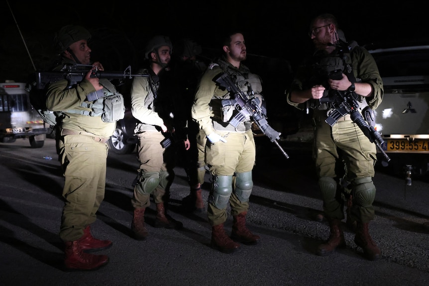 Israeli soldiers lit up by car head lights during an evening patrol.