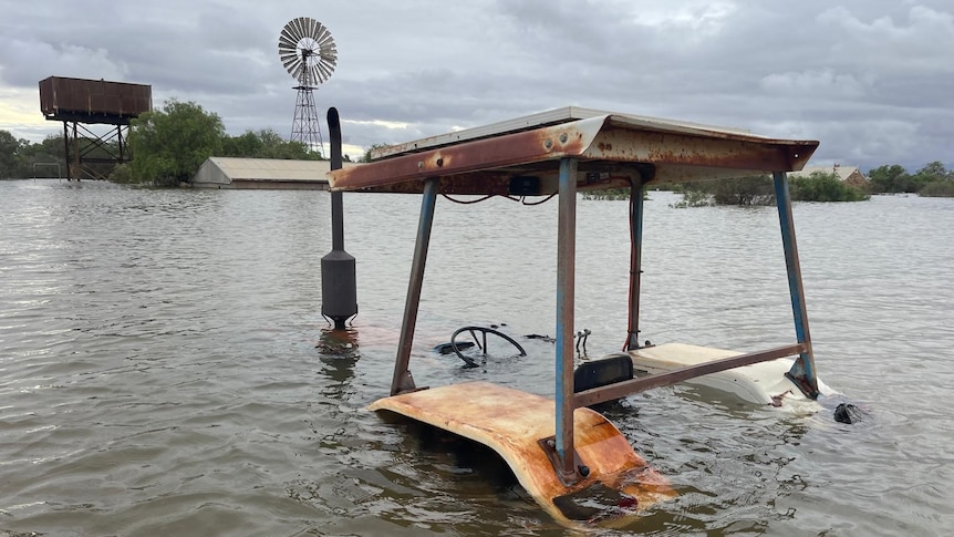 A tractor under water at flooded outback sheep station.  