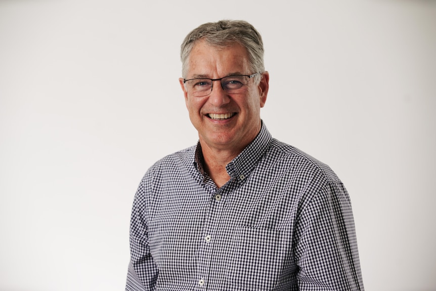 A headshot of a smiling Steve in a checkered black and white shirt.