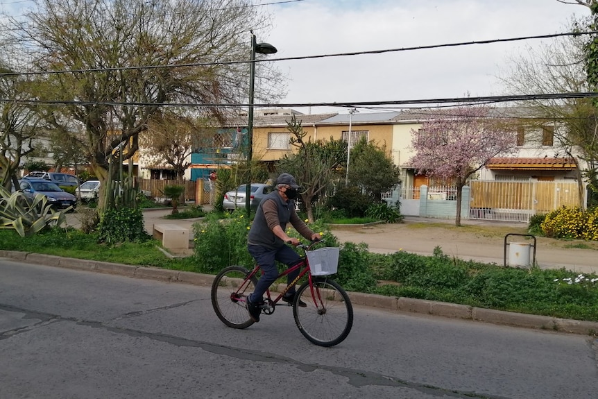 A man riding a bike wearing a face mask.