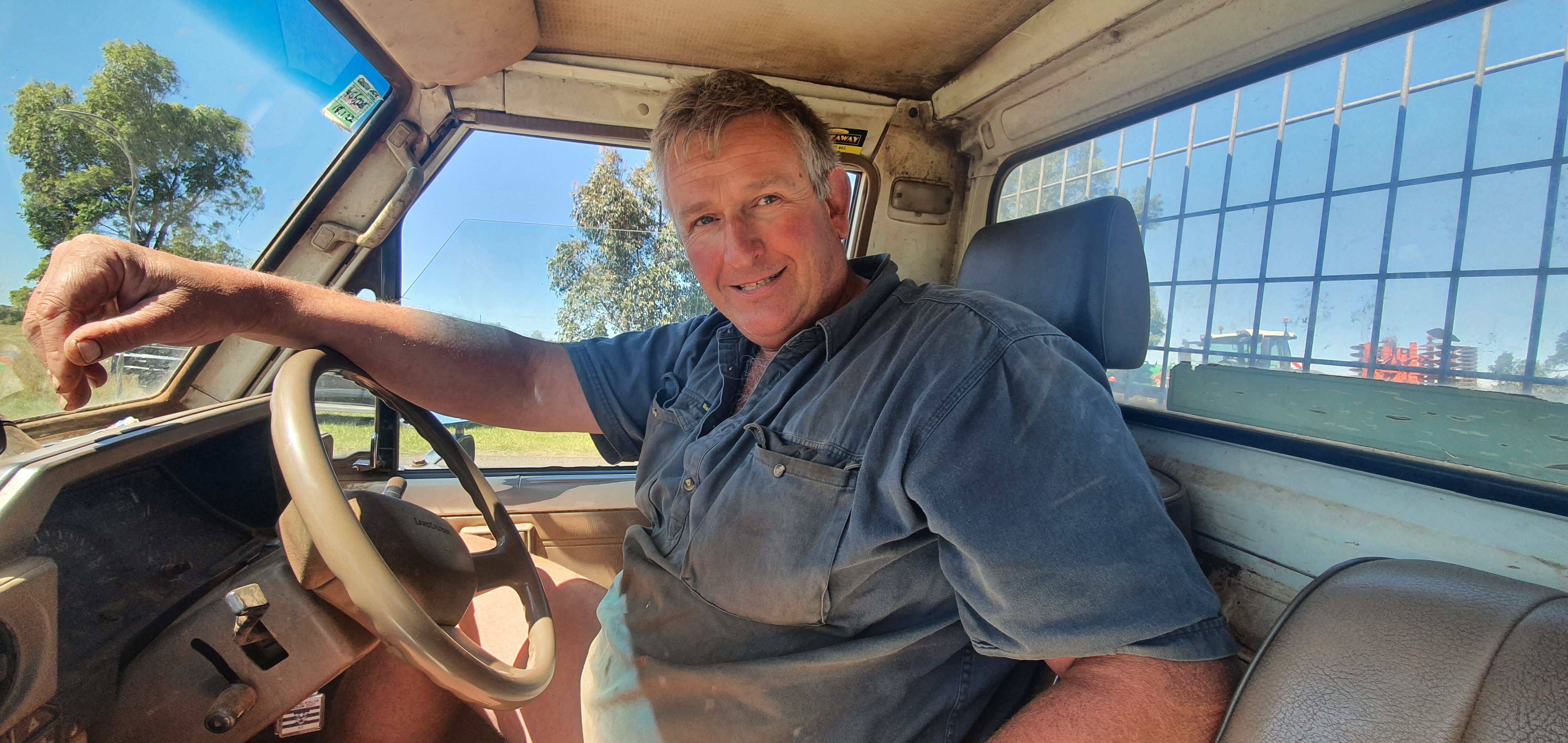 A farmer in a ute, smiling.