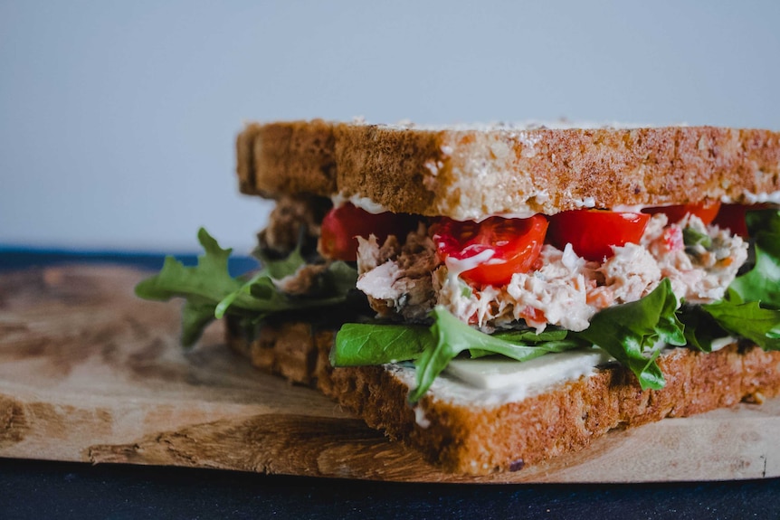 Close up of tuna fish salad sandwich on a wooden chopping board