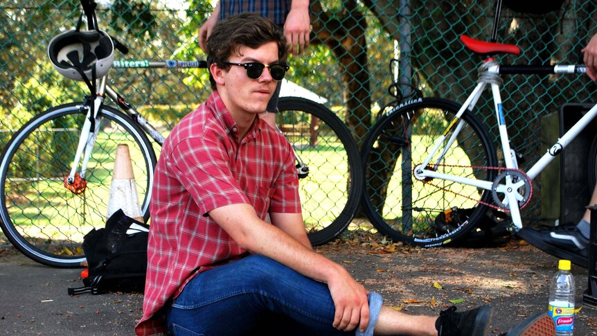 A young bike polo player sits on the sideline